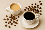 Twee witte kopjes koffie, één zwart en één met melk, op beige ondergrond met koffiebonen