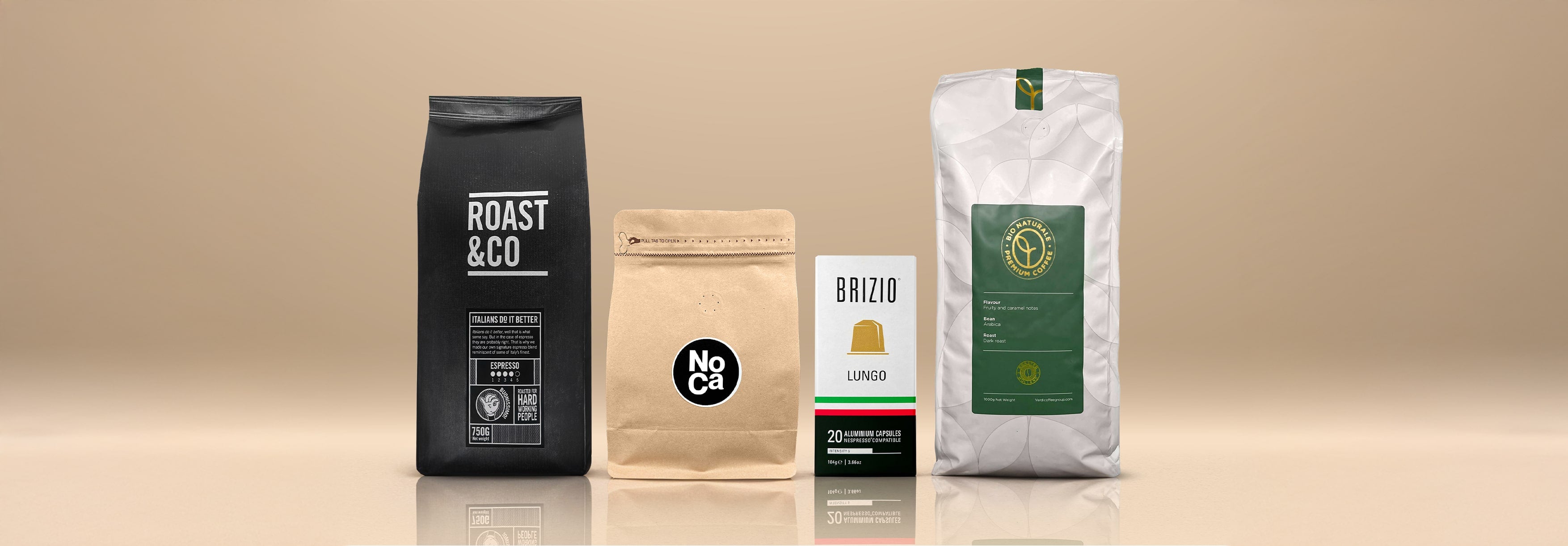 Groepsfoto van vier verschillende koffieproducten: zwarte Roast & Co zak, bruine NoCa zak, Brizio Lungo cups doosje en een witte Organic Coffee zak, op een beige achtergrond.