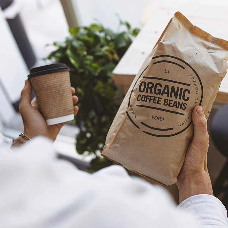 Vers gebrande biologische koffiebonen van Verdi, geserveerd in een duurzame to-go beker.